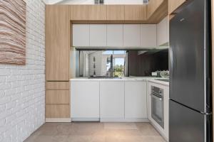 a kitchen with white cabinets and a stainless steel refrigerator at Apollo Bay Gone Surfin in Apollo Bay +15 photos
