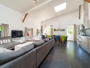a living room with a large couch and a kitchen at Het Grootenhuis in Olst