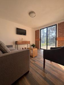 a living room with a couch and a large window at Cabañas Los Angeles in Valle de Bravo