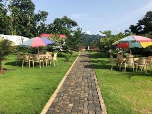 a brick path with tables and chairs with umbrellas at Resort Ideal Forest in São Tomé