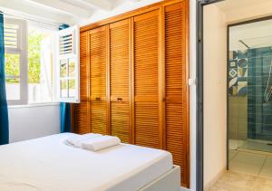 a bedroom with wooden shutters and a bed and a shower at Villa Caryota, Panorama Montagnes & Piscine 9m in Le Marin +33 photos