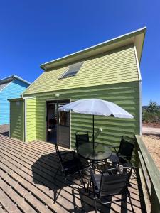 a table and chairs with an umbrella on a deck at CIRyT La Montaña - Eco Cabañas y Turismo Rural in Tomé