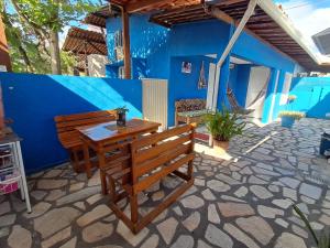 a patio with a wooden table and bench in front of a blue wall at Pousada Odoyá Beach - Casal in Conde