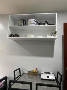 a table with two chairs and a shelf with pots and pans at Maple Leaf Residences - Unit 2 in Southern Davao