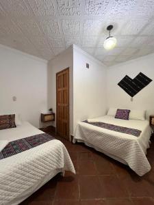 a bedroom with two beds and a ceiling at Hotel Makani in Panajachel