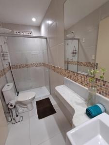 a white bathroom with a toilet and a sink at Pousada Odoyá Beach - Quádrupla in Conde