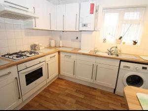 a kitchen with white cabinets and a sink and a stove at Joni Bungalow-2-Bedroom HOME in Slades Green +17 photos