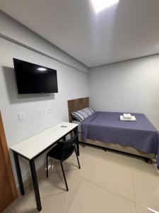a room with a bed and a desk and a tv at Studio em Anápolis in Anápolis