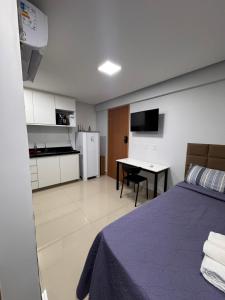 a bedroom with a bed and a table and a kitchen at Studio em Anápolis in Anápolis