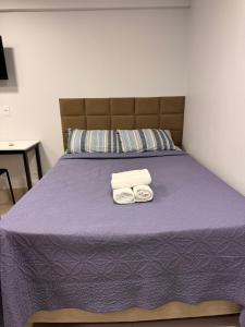 a bedroom with a purple bed with towels on it at Studio em Anápolis in Anápolis