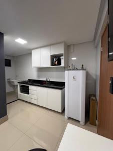 a kitchen with white cabinets and a white refrigerator at Studio em Anápolis in Anápolis