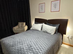 a bedroom with a large bed and a chair at Apartamento no Centro 2 Wi-Fi Garagem in Vacaria