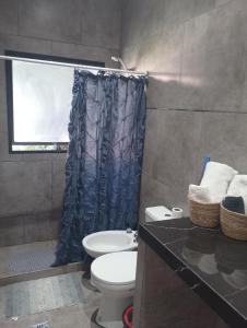 a bathroom with a toilet and a blue shower curtain at Lo de Mili in General Juan Madariaga