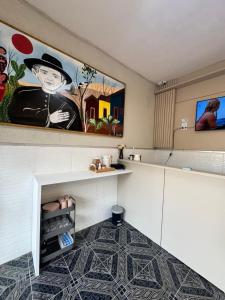 a kitchen with a painting on the wall and a shelf at Pousada do Horto in Juazeiro do Norte +14 photos