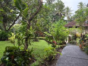 a walkway through a garden with trees and plants at Raka Rai Bungalows in Ubud