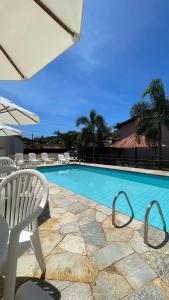 a large swimming pool with chairs and a table and a chair at Casa Aroeira Sahy in Barra do Sahy