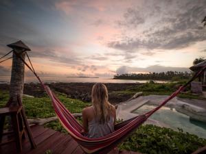 a woman sitting in a hammock looking at the ocean at Simeulue Surflodges in Lasikin