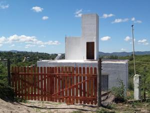 a small white building with a fence in front of it at Mountain View & Comfort in Villa Santa Cruz del Lago