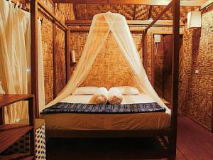 a bed in a room with a mosquito net at Simeulue Surflodges in Lasikin +32 photos