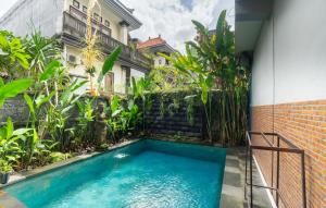 a swimming pool in front of a building with a house at Pak Vo House by The Travel Ubud Bali in Ubud