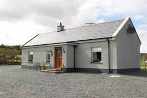 a small white house with a gravel driveway at Pat Larry's Cottage in Greencastle