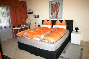a bedroom with a large bed with an orange comforter at Loreley Hills in Sankt Goarshausen