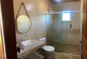 a bathroom with a toilet and a sink and a mirror at Refúgio da Nicinha a 7 min do Centro Histórico in Paraty