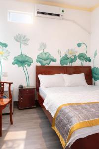 a bedroom with a bed with flowers painted on the wall at Nam Phương Hotel Sa Đéc in Sa Ðéc