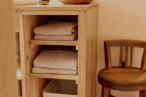 ein Holzregal mit Handtüchern und ein Holzstuhl in der Unterkunft 一棟貸しヴィラmatai in Kitsuki