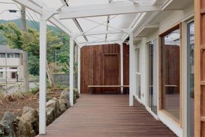 eine hölzerne Veranda mit Pergola an einem Haus in der Unterkunft 一棟貸しヴィラmatai in Kitsuki