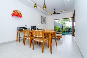 a dining room with a wooden table and chairs at Made Ubud Villa by Bali Cabin in Ubud