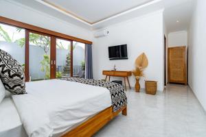 a bedroom with a large bed and a television at Made Ubud Villa by Bali Cabin in Ubud