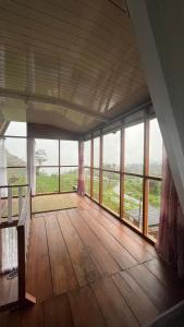 a large room with wooden floors and large windows at Padangsari Cabin 2 in Diyeng