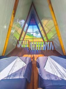 two beds in a room with a large window at Padangsari Cabin 2 in Diyeng