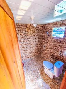 a bathroom with a toilet and a brick wall at Padangsari Cabin 2 in Diyeng +12 photos