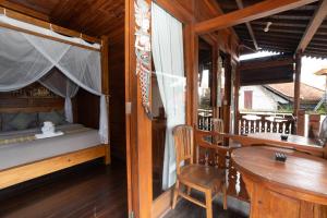 a bedroom with a bed and a table and a chair at Pak Vo House by The Travel Ubud Bali in Ubud