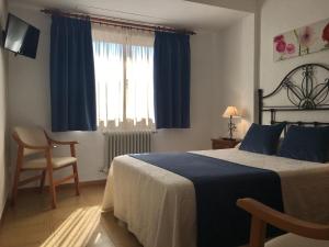 a bedroom with a bed and a chair and a window at Hostal La Noria in Ruidera