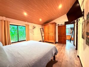 a bedroom with a white bed and a window at Casa Del Bambu in Puerto Jiménez