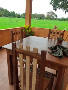 a wooden table and chairs with a view of a field at Paddy Wind Eco Lodge Sigiriya in Kibissa