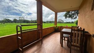 a porch with a table and chairs and a view of a field at Paddy Wind Eco Lodge Sigiriya in Kibissa