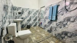a bathroom with a toilet and a marble wall at Paddy Wind Eco Lodge Sigiriya in Kibissa