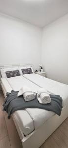 a white bed with two towels on top of it at Bianca Apartment in Bissone +17 photos