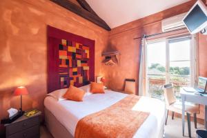 a bedroom with a bed and a desk and a window at Logis hotels Les Glycines in Melle