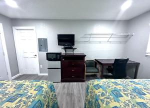 a hotel room with a bed and a desk with a television at Lemon Bay Motel in Englewood +12 photos