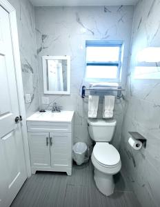 a white bathroom with a toilet and a sink at Lemon Bay Motel in Englewood