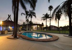 a pool with palm trees in front of a building at Centrepoint Midcity Motor Inn in Warwick