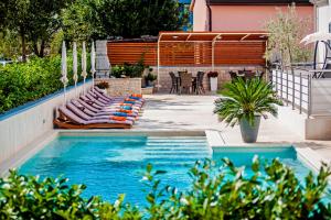 a swimming pool with lounge chairs and a table at Apartments Kimi in Rovinj