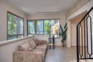 a living room with a couch and some windows at Keter HaSimta - כתר הסמטה in Safed