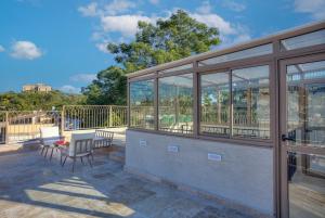 a glass house with a table and chairs on a patio at Keter HaSimta - כתר הסמטה in Safed