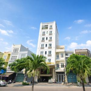 a tall white building with palm trees in front of it at Selima Hotel in Quy Nhon